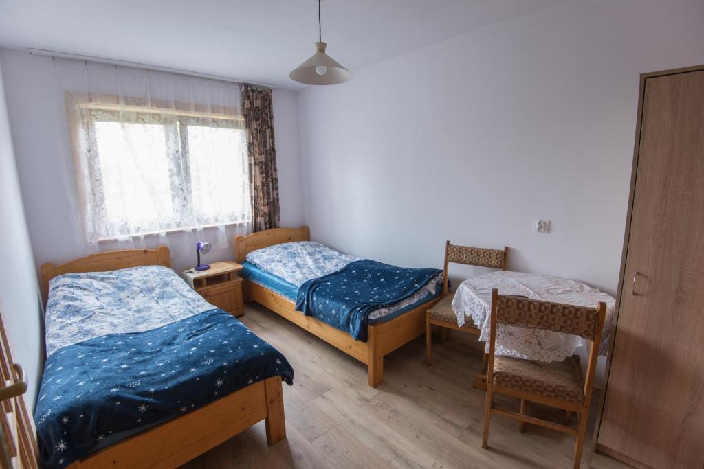 pokój z 2 łóżkami, szafą, szafką nocną, stołem i krzesłami w obiekcie Willa Pod Jasieniami w mieście Białka Tatrzanska