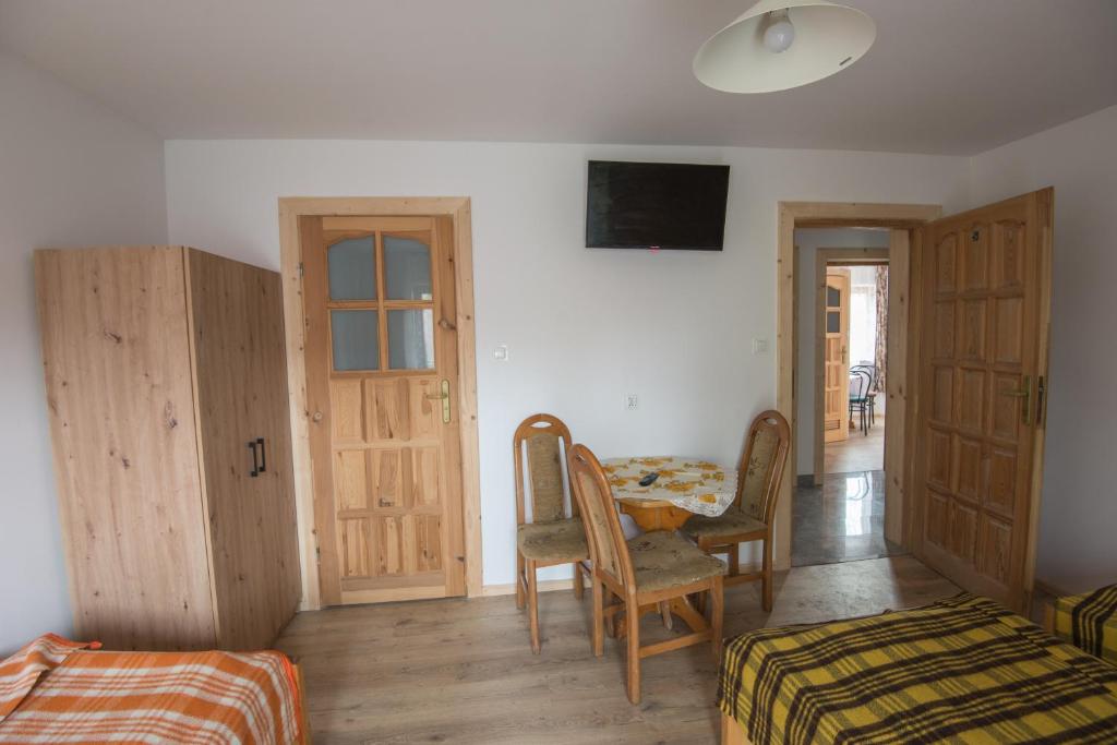 pokój z 2 łóżkami, telewizorem, stołem i krzesłami w obiekcie Willa Pod Jasieniami w mieście Białka Tatrzanska