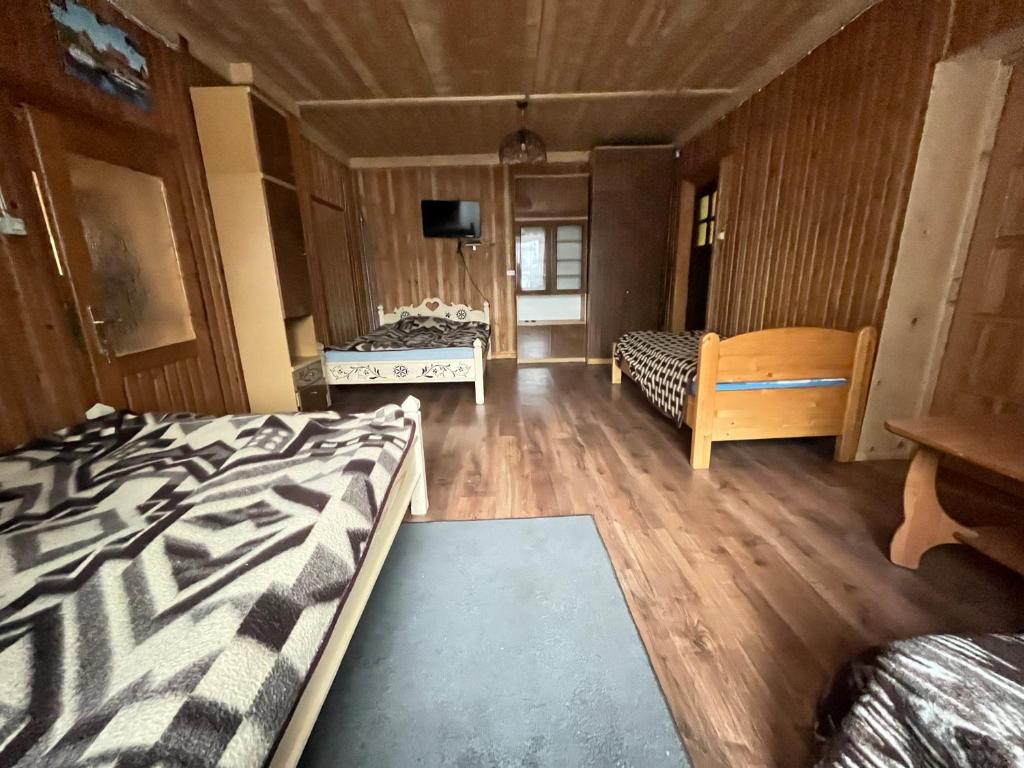 pokój z 3 łóżkami, stołem i telewizorem obiekt Pokoje u Cekusa w mieście Białka Tatrzanska