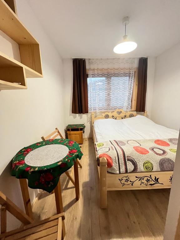 pokój z 1 łóżkiem, wiszącą szafką, stołem i krzesłami w obiekcie Willa Pod Jasieniami w mieście Białka Tatrzanska